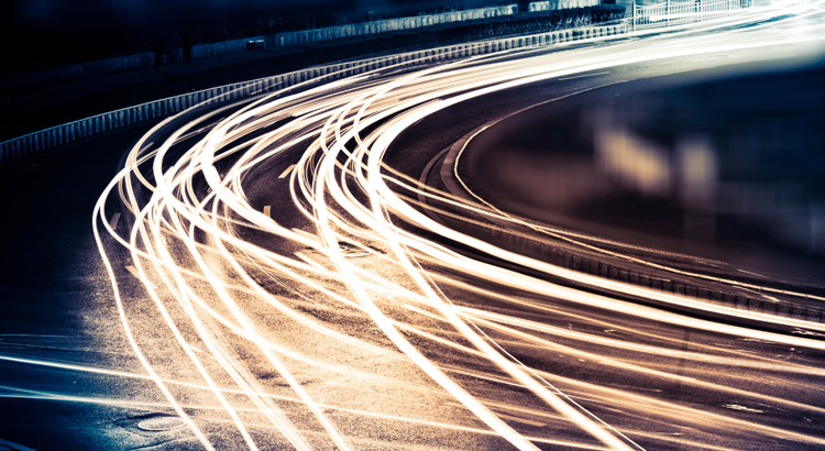 Streaking car tail lights on road at night.